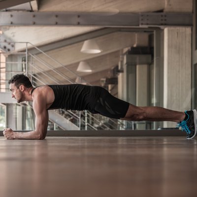 Mid adult man doing plank exercise with towel