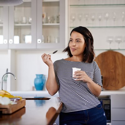 A woman on an acid reflux diet eating low-fat yogurt in her kitchen
