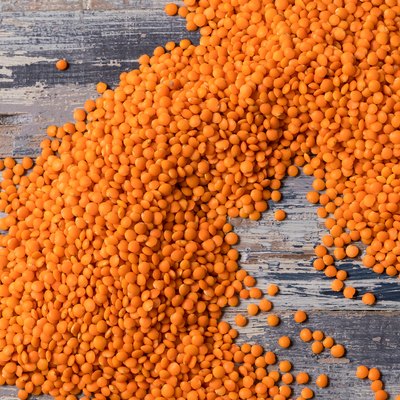 Background pattern with orange lentils seeds of annual legume plant, vegetable protein, flat lay.