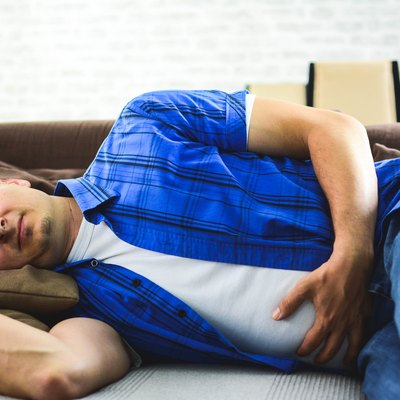 Man lying on sofa looking sick in the living room