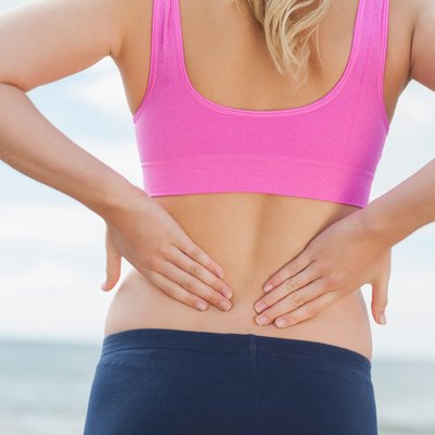 Mid section of toned woman from back pain on beach