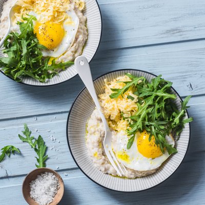 Low-FODMAP recipe oatmeal with fried egg and arugula on a blue background