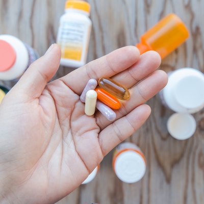 A hand holding a bunch of pills in an open palm.