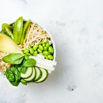 Vegan, detox green Buddha bowl recipe with quinoa, avocado, cucumber, spinach, tomatoes, mung bean sprouts, edamame beans, daikon radish. Top view, flat lay, copy space