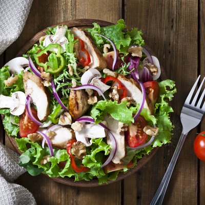 Grilled chicken salad shot from above on rustic wood table