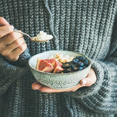 Woman in woolen sweater eating rice coconut porridge