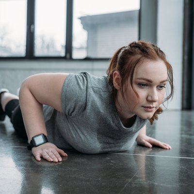 Obese girl performing push ups in gym