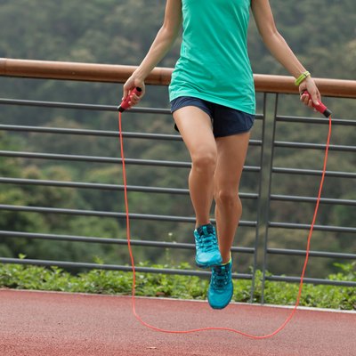 Woman athlete jumping rope on spring forest trail. woman fitness workout wellness concept.