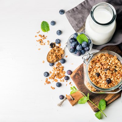 Healthy breakfast ingrediens. Homemade granola in open glass jar, oat milk