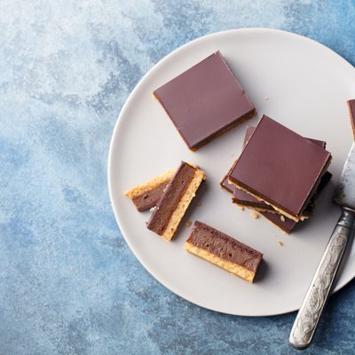 Chocolate caramel slices, bars, millionaires shortbread on a grey plate. Blue background. Top view.
