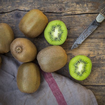 Kiwis (Actinidia deliciosa) and pocketknife on wooden table