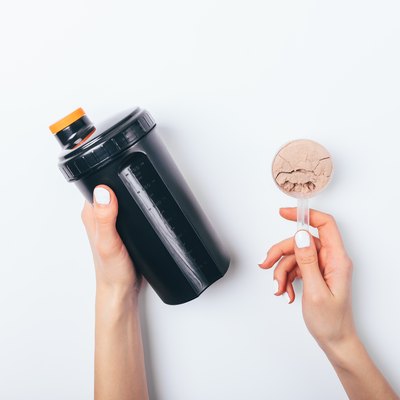 Female's hands holding scoop of chocolate protein powder