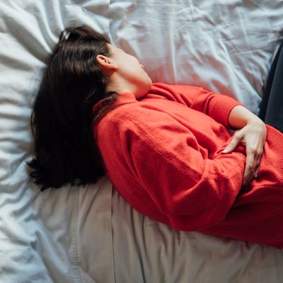 woman has stomachache , lying on the bed