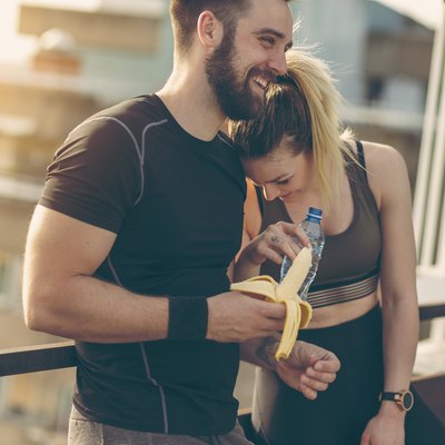 Couple resting after a workout having a banana and water, which is a good Gatorade alternative