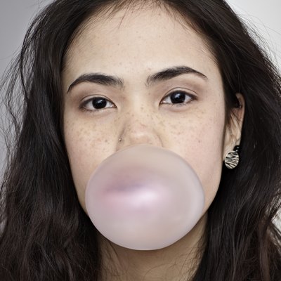Germany, Cologne, Young woman blowing bubble gum