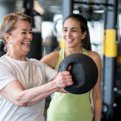Adult woman exercising at the gym with a personal trainer