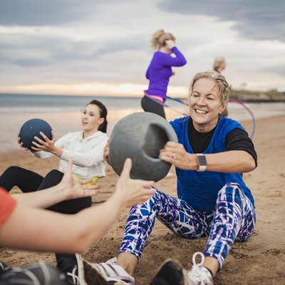 Woman Doing Weighted Ball Exercises During Boot Camp Workout Class