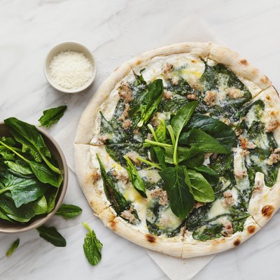 Pizza with chopped meat, spinach and cream sauce