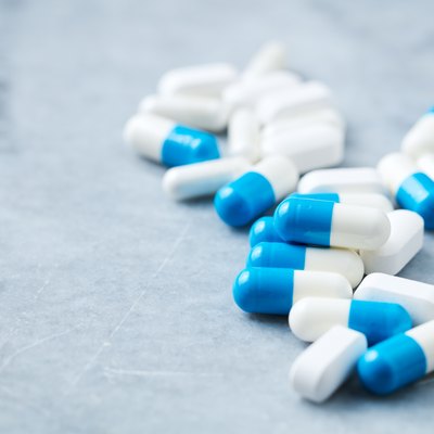 Tri-Creatine Malate and Arginine capsules and BCAA amino acids. Bodybuilding food supplements on bright stone background. Close up.