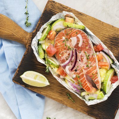 Raw salmon steak with vegetables in a foil boat