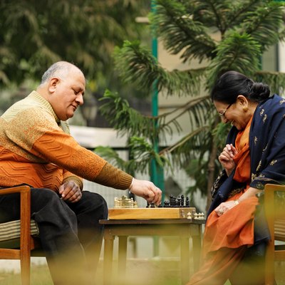 couple seated in garden playing chess