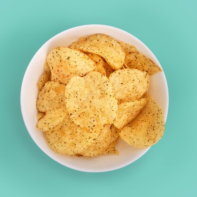 Close-up of potato chips in a bowl on turquoise background to avoid before colonoscopy procedure