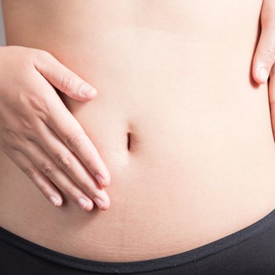 Female hands on the stomach on white background.