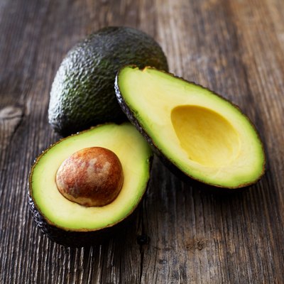 Whole and sliced avocado on wood
