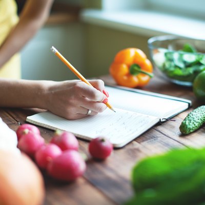 Woman writing meal plan in a journal