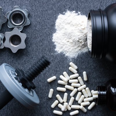 dumbbells, protein and amino acids on a gray background