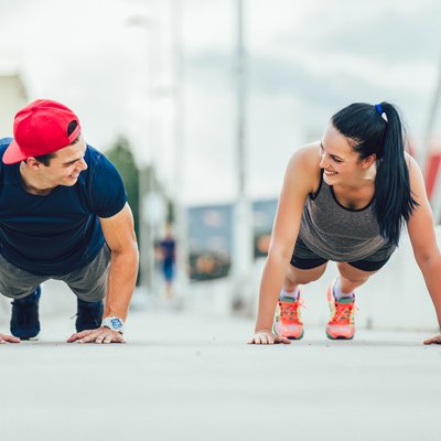 Happy couple doing push-ups outdoors on the bridge