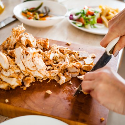 Woman cutting lean chicken breast.