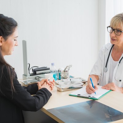 Senior female doctor meet the patient discussing and making notes about symptom problem. Health care and client service in medicine concept.