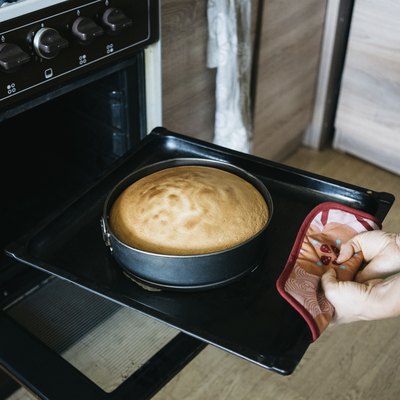 Midsection of woman preparing cake in oven at home