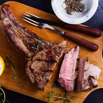 bone-in ribeye steak on cutting board ready to eat, top view