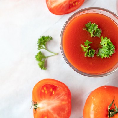 Glass of tomato juice and fresh tomatoes on marble table background. copy space