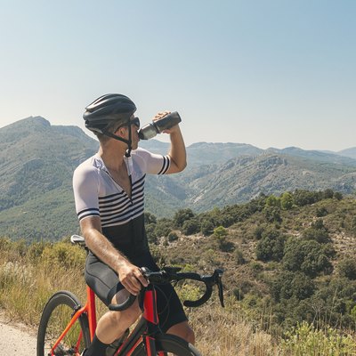Cyclist drinking from water bottle at summit during summer workout