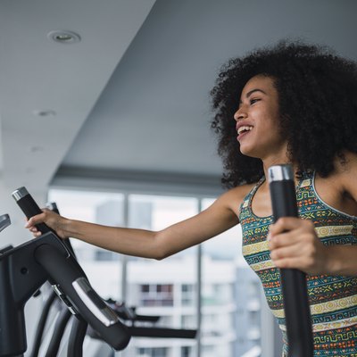 Smiling young woman on step machine in gym