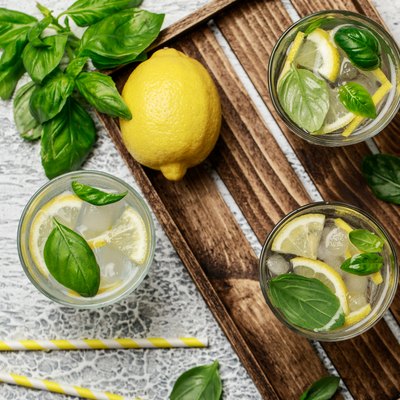 Summer basil lemonade on grey background. Fresh summer cocktail with basil, lemon and ice cubes. Homemade fresh lemonade with lemon and basil. Food and drink concept