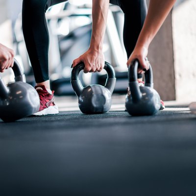 Lifting weights, low angle image. Athletes with kettle bells, close-up.