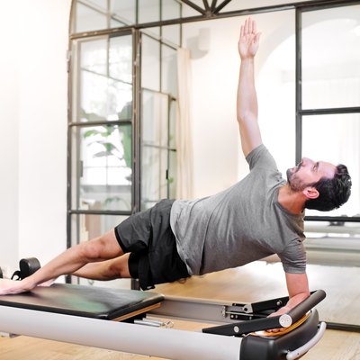 Fit man doing pilates side elbow plank exercises