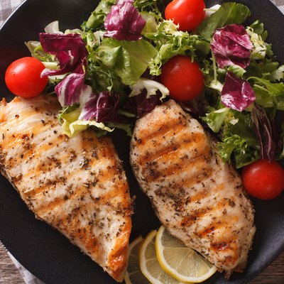 Close-up view of grilled chicken breast with mixed salad
