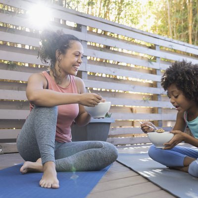 what to eat before a workout mother and daughter eating cereal on yoga mats on deck