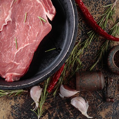 Raw beef steak with spices and herbs.