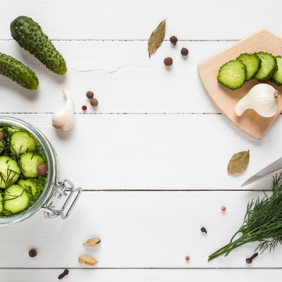 Cucumbers ready for pickling and ingredients on white table.
