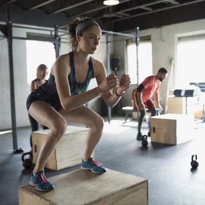 Focused woman jump squats in gym exercise class