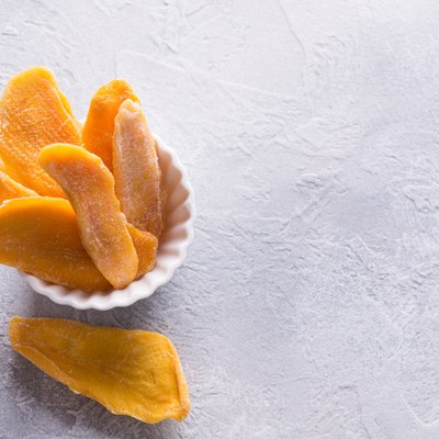 Dehydrated and dried mango chips in white bowl. Close up.