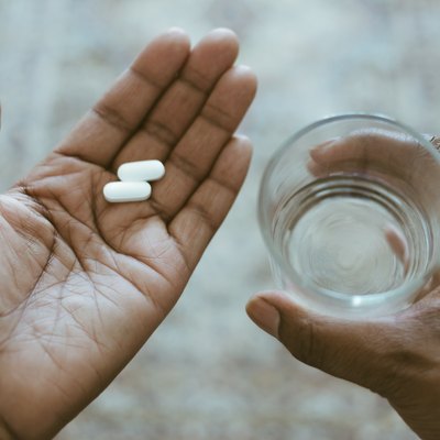 Close-Up View of Hands Holding Pills and Water