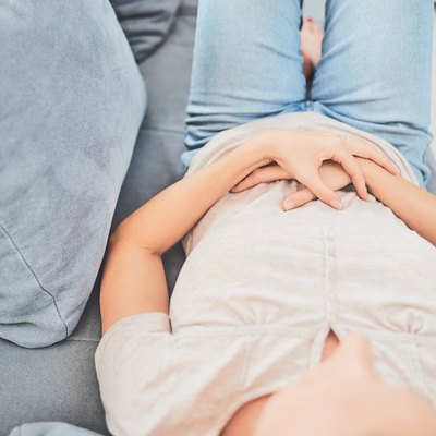 Woman with stomach issues / problems while lying on the couch.