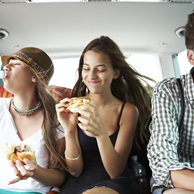 Three teenage friends having a snack in car
